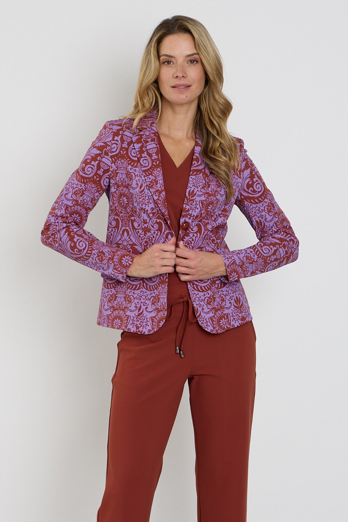 Mi Piace reiskostuumblazer in brique met barokprint en hyacintkleur, getoond op een model met knoopsluiting en revers.