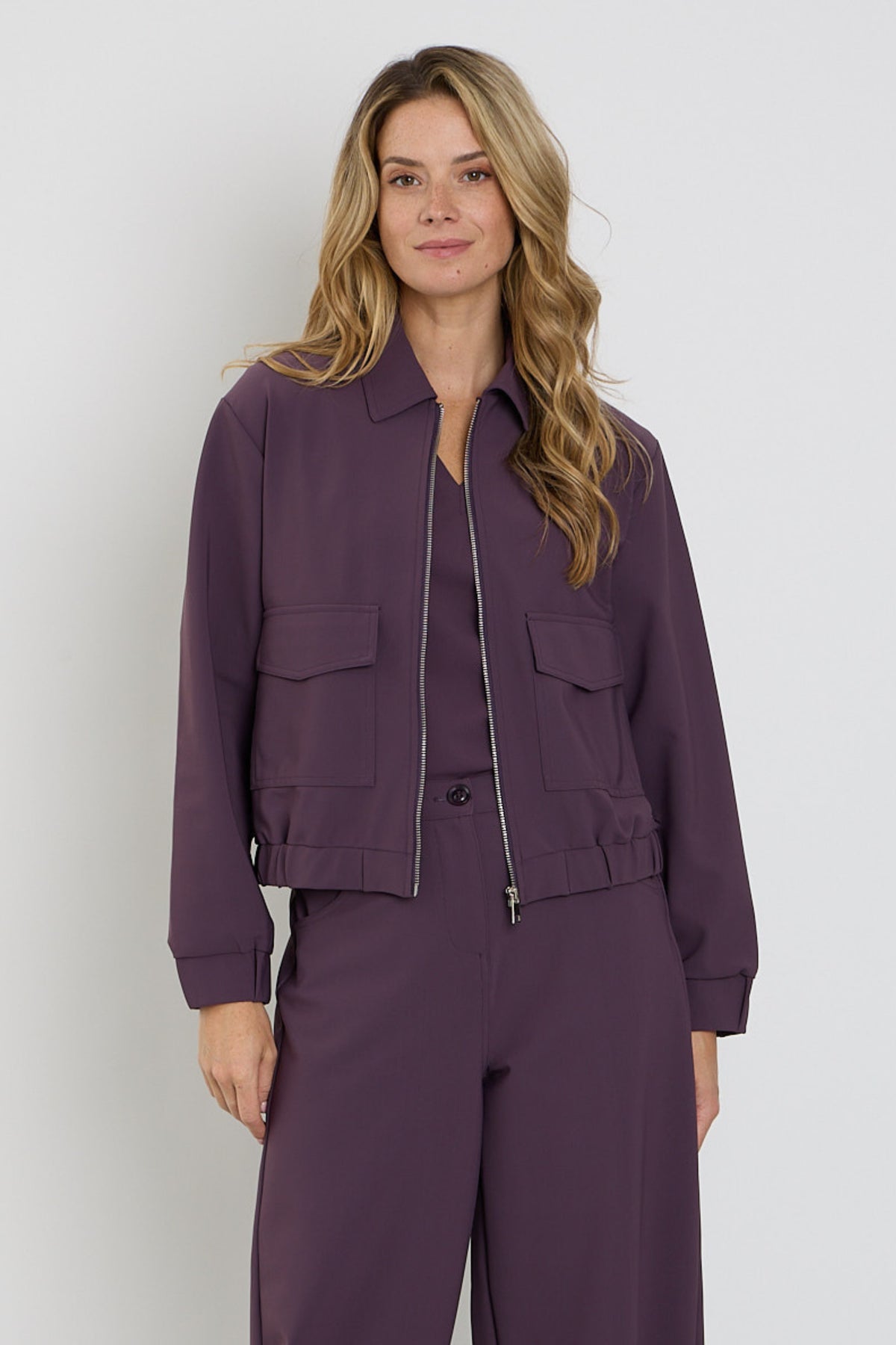 Mi Piace Travel Top Plum Perfect 202271, donkerpaarse reisblouse met korte mouwen en elegante snit, hangend op een kleerhanger.