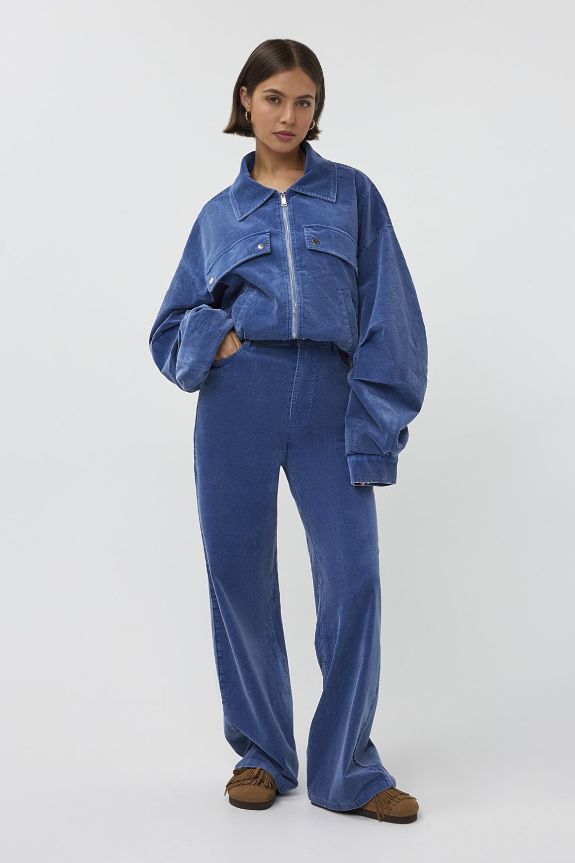 Lichte blauwe jas Gijsje van Studio Amaya, met rits en capuchon, gedragen door een model op een neutrale achtergrond.
