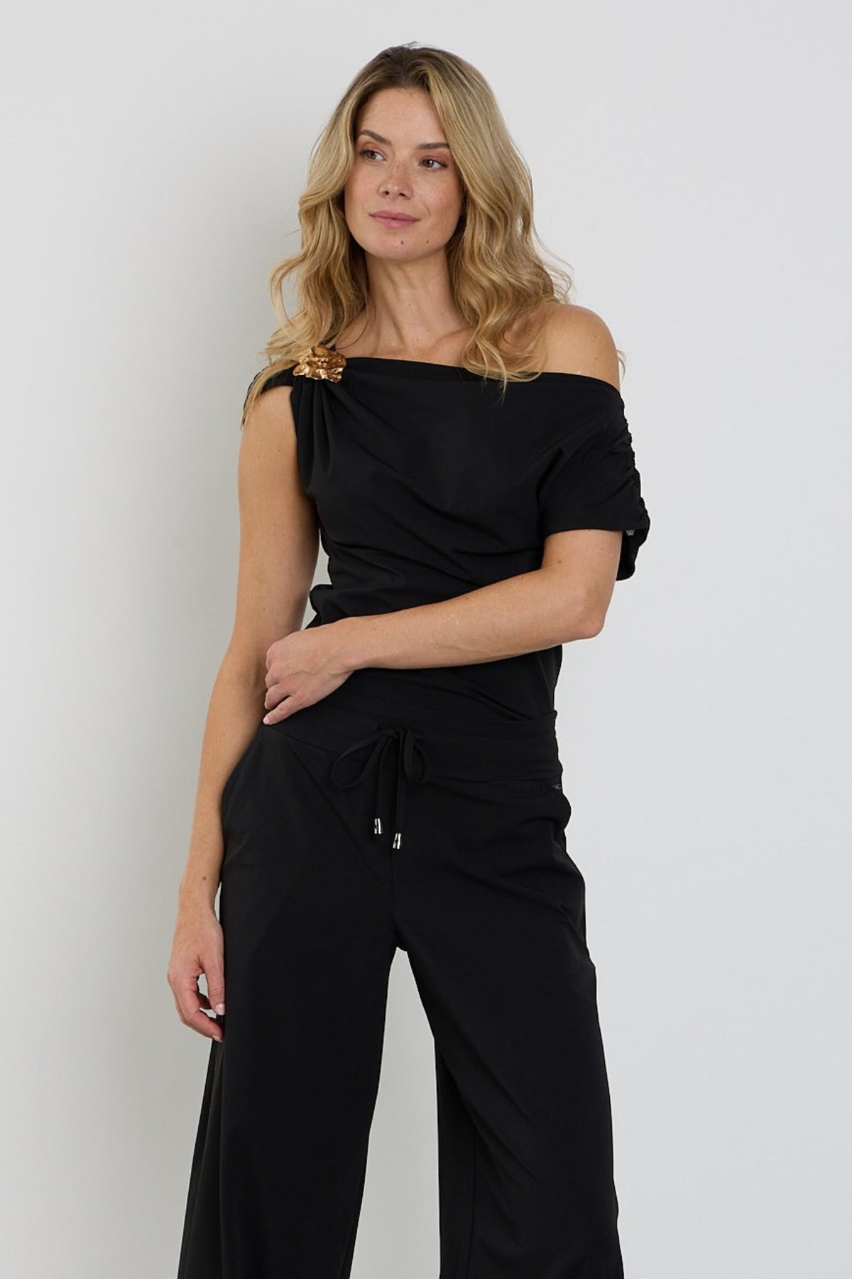 Zwarte Travel Top Broche van Mi Piace met gedetailleerde afwerking en elegante uitstraling, zichtbaar op de afbeelding.