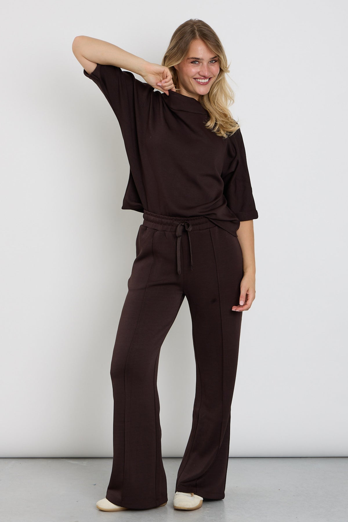 Donkere FQLucinda Mole broek van Freequent met rechte pasvorm en elastische taille, gelegd op een witte achtergrond.