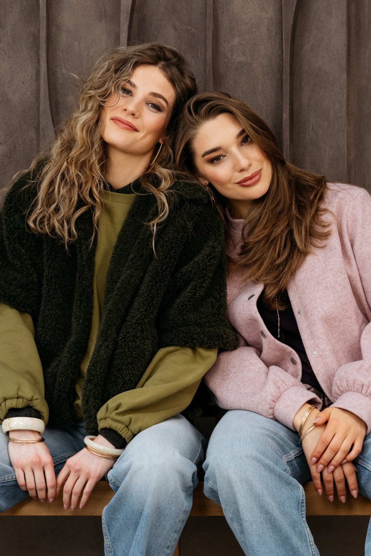 Donker kaki jas Chelsey van &Co woman, modieus en warm, met ritssluiting en kraag, zichtbaar in de afbeelding.