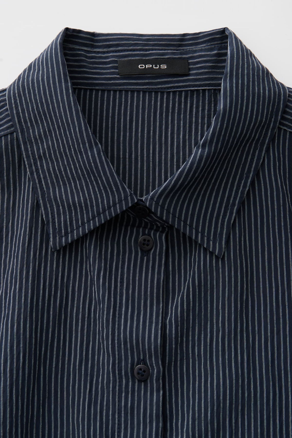 Blouse Flaneta Coal Blue van Opus, getailleerd met lange mouwen en knoopsluiting, ligt plat op een witte achtergrond.