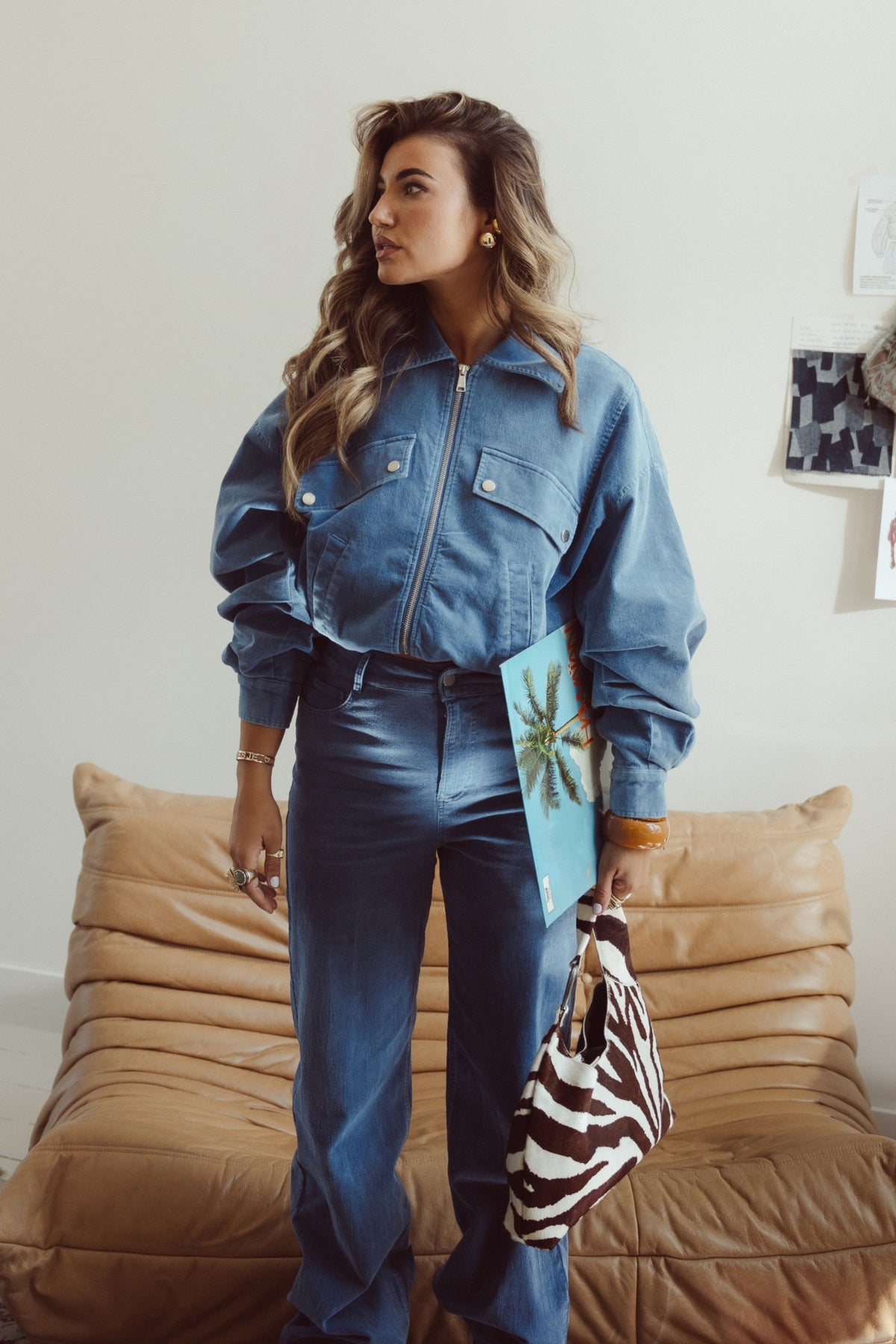 Blauwe Gijsje jas van Studio Amaya met ritssluiting en capuchon, gedragen door een model op een witte achtergrond.