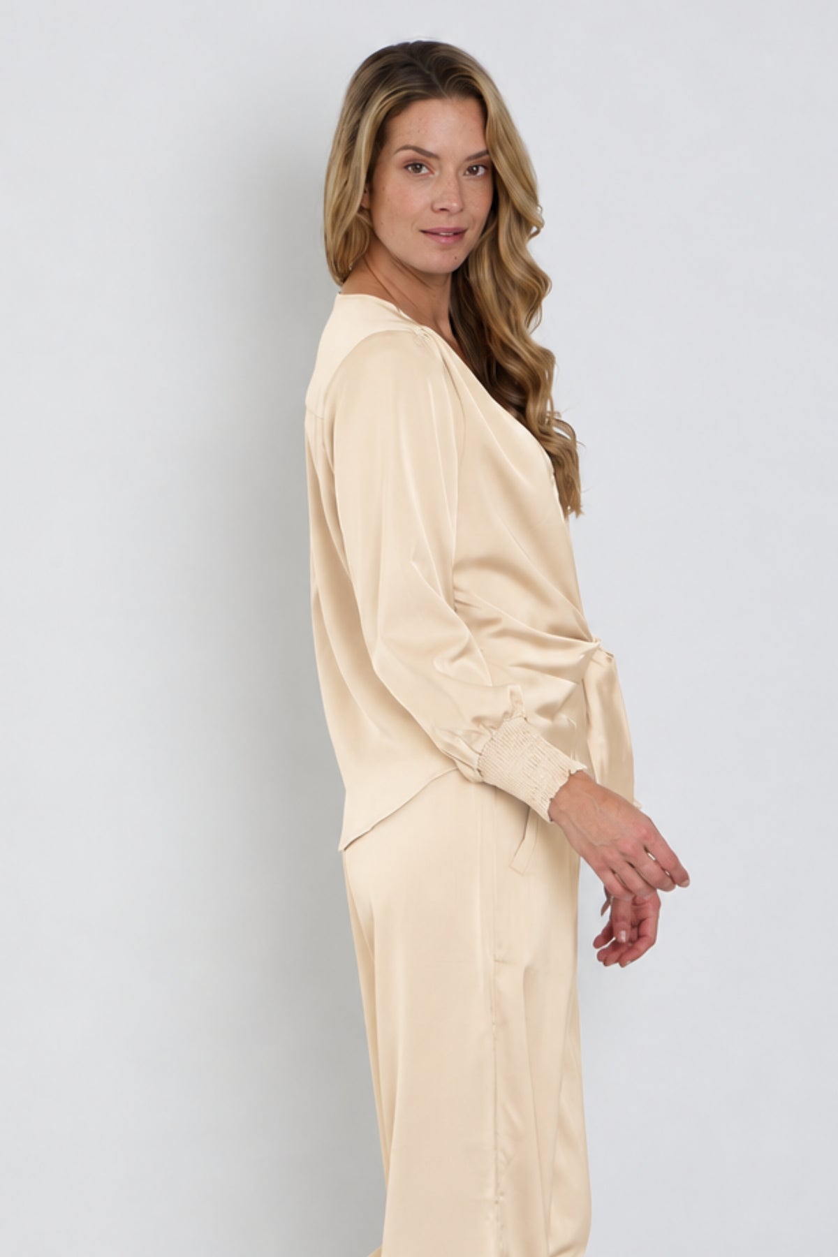 Mooie satijnen blouse met knoopdetail in zandkleur van Mi Piace, getoond in close-up met knoop en stoftextuur