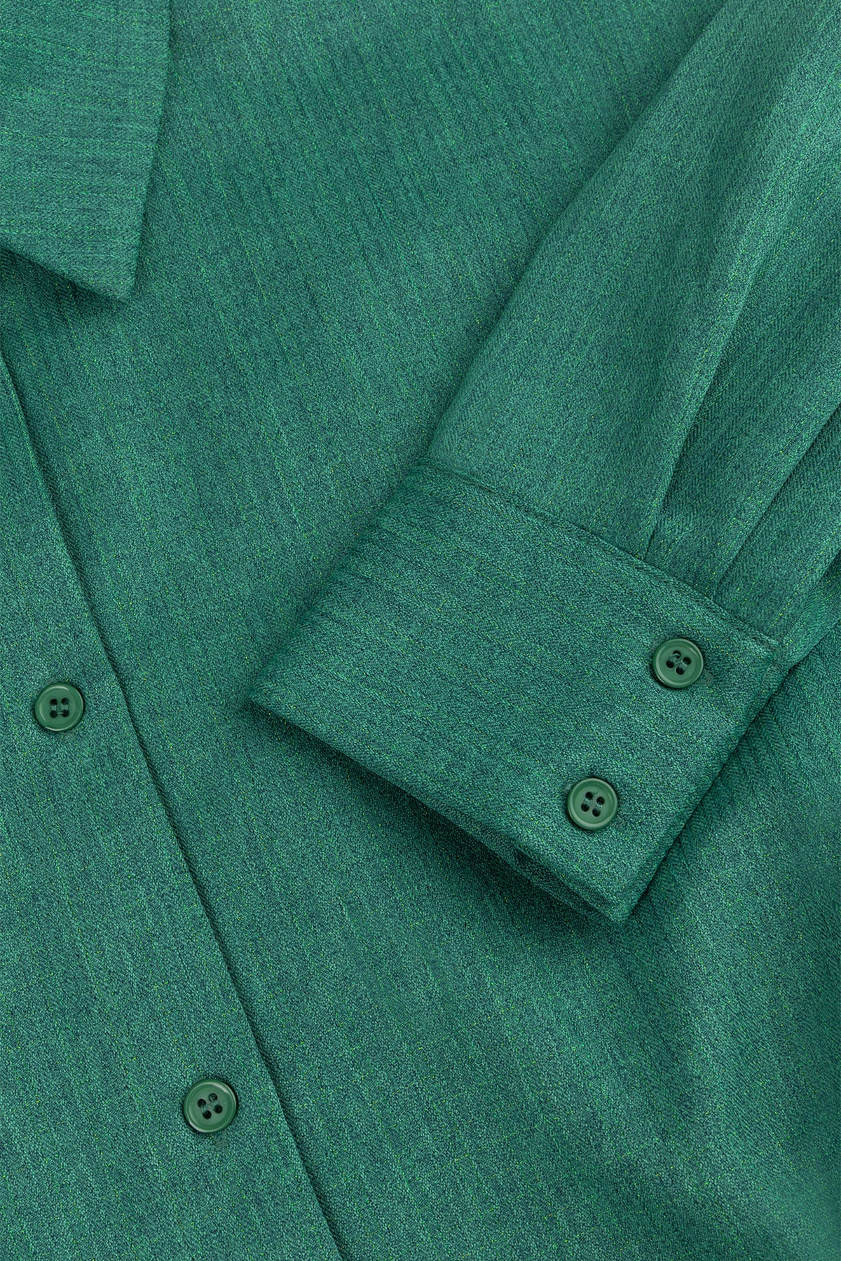 Groene blouse Niva van Studio Amaya met losse pasvorm en lange mouwen, hangend aan een kapstok.