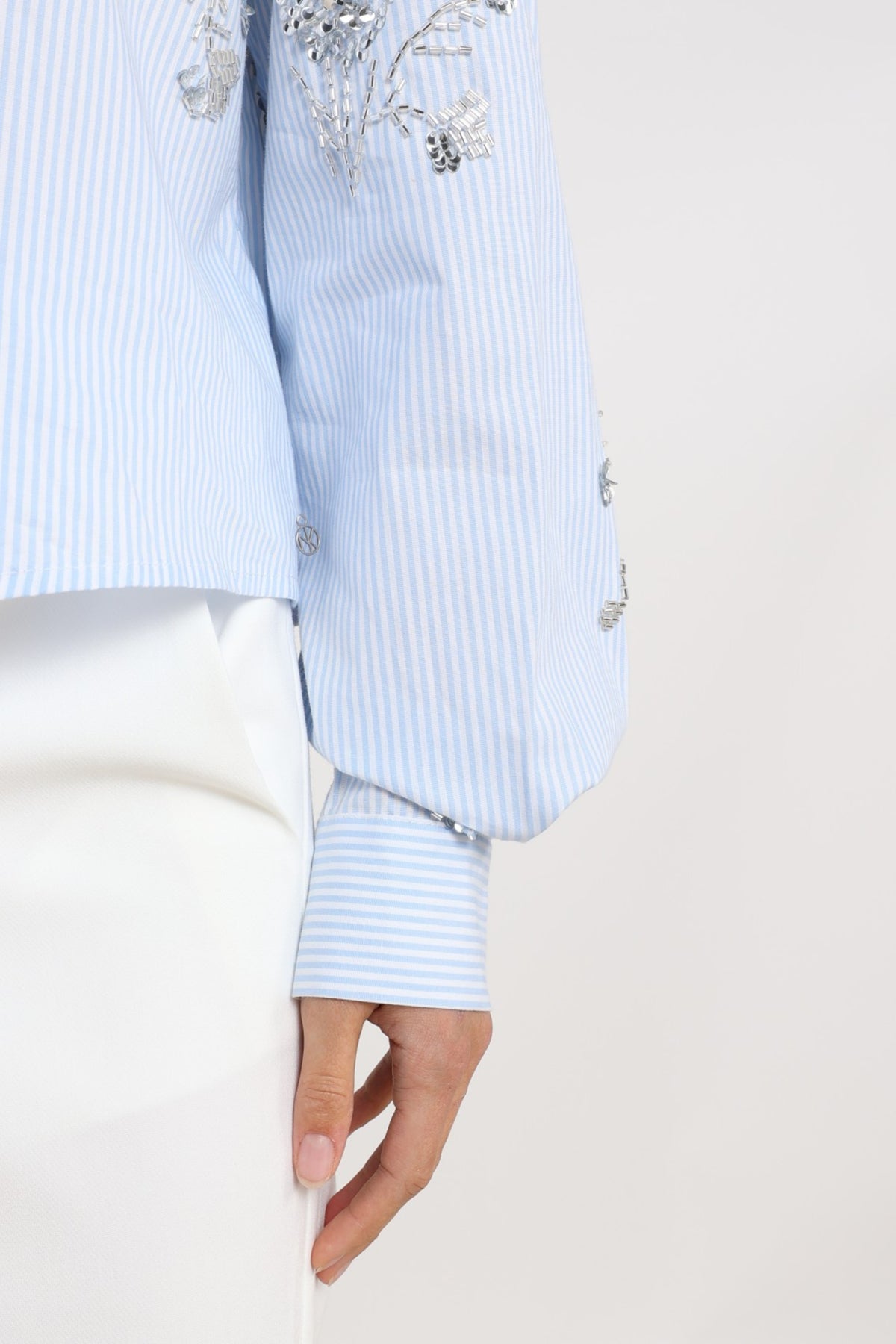 Blouse Adora Stripe Cloudy Offwhite van Nukus, witte blouse met blauwe streepdetails en losse pasvorm, zichtbaar in de afbeelding