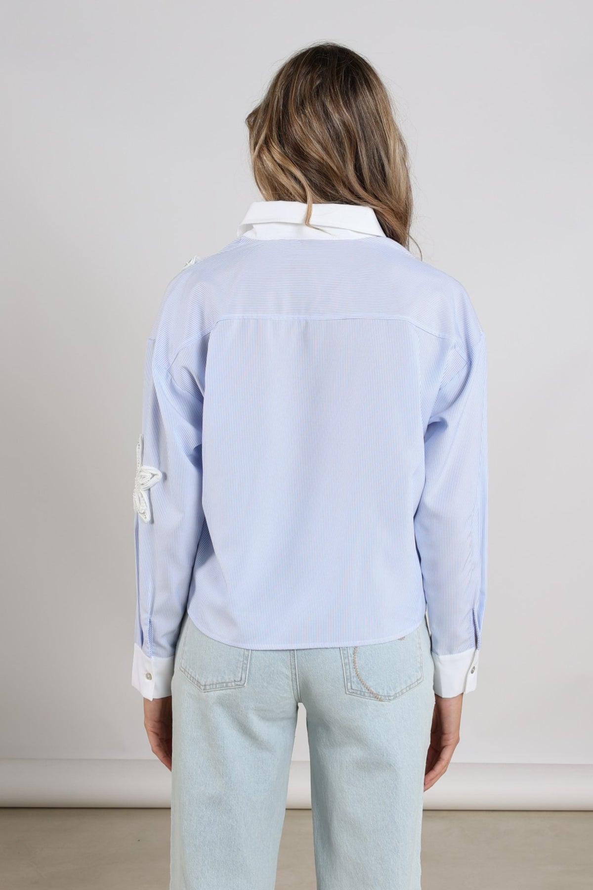 Nukus Tessa Stripe Offwhite blouse met blauwe en grijze strepen, lange mouwen en losvallende pasvorm, gelegen op een witte achtergrond