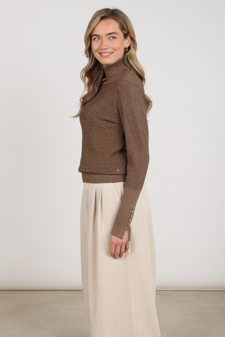 Taupe lurex trui Sylvia van Nukus, zachte knitwear met glanzende details, zichtbaar in de afbeelding.