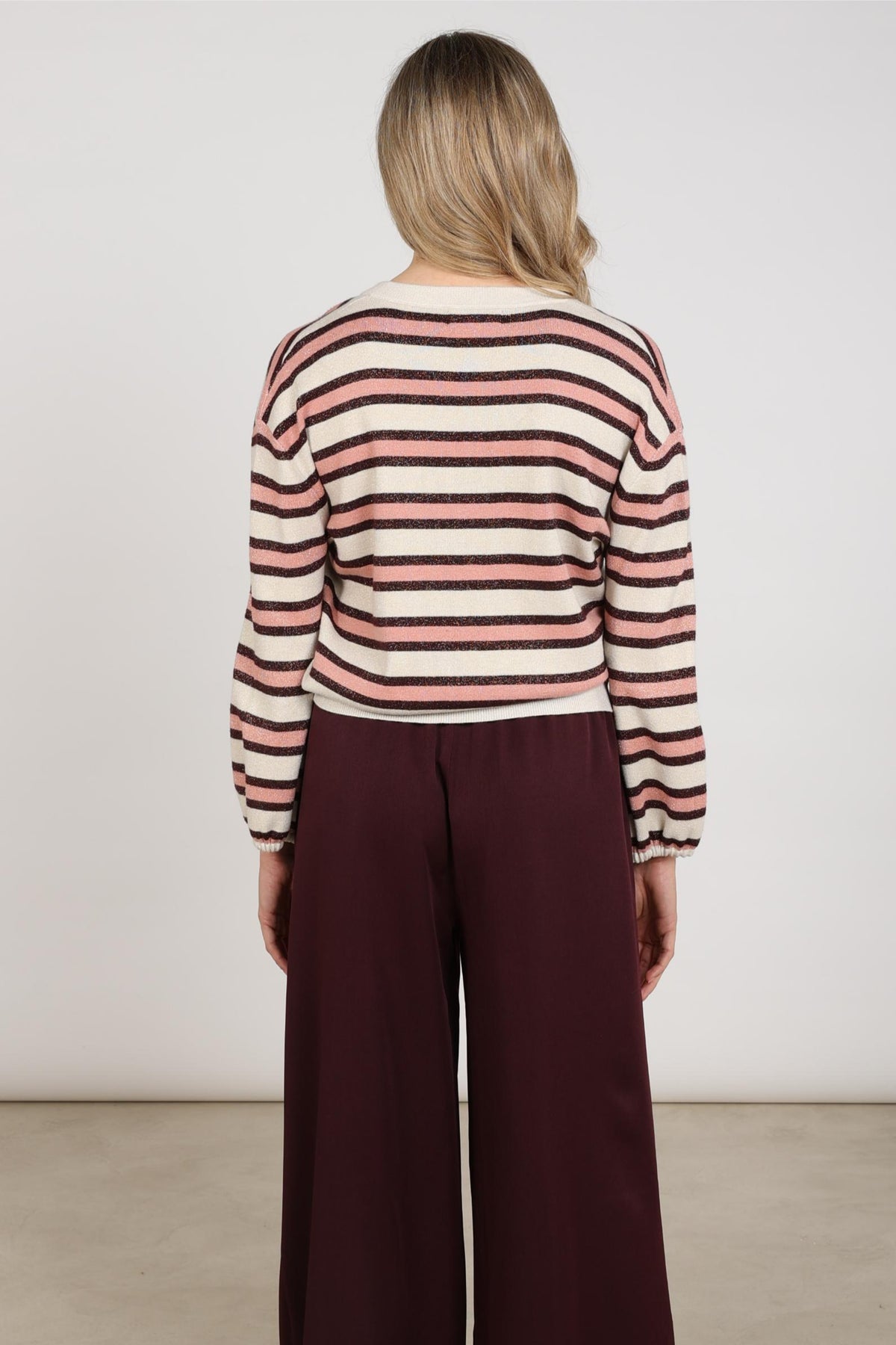 Nukus Kim Stripe Sand Rose trui met roze en beige strepen, zachte katoenen stof, gedragen door een model.