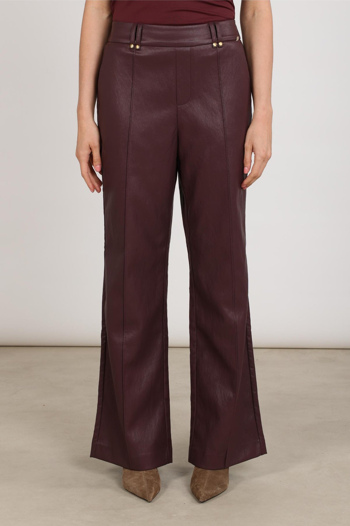 Nukus Jill PU Cherry broek in rood met comfortabele pasvorm en ritsdetail, zichtbaar op de afbeelding.