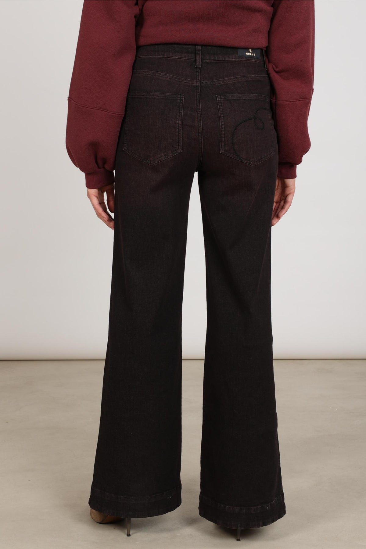 Nukus Abby Cherry jeans in donkerrood met rechte snit en vijf zakken, gedragen door een model, close-up van de pasvorm