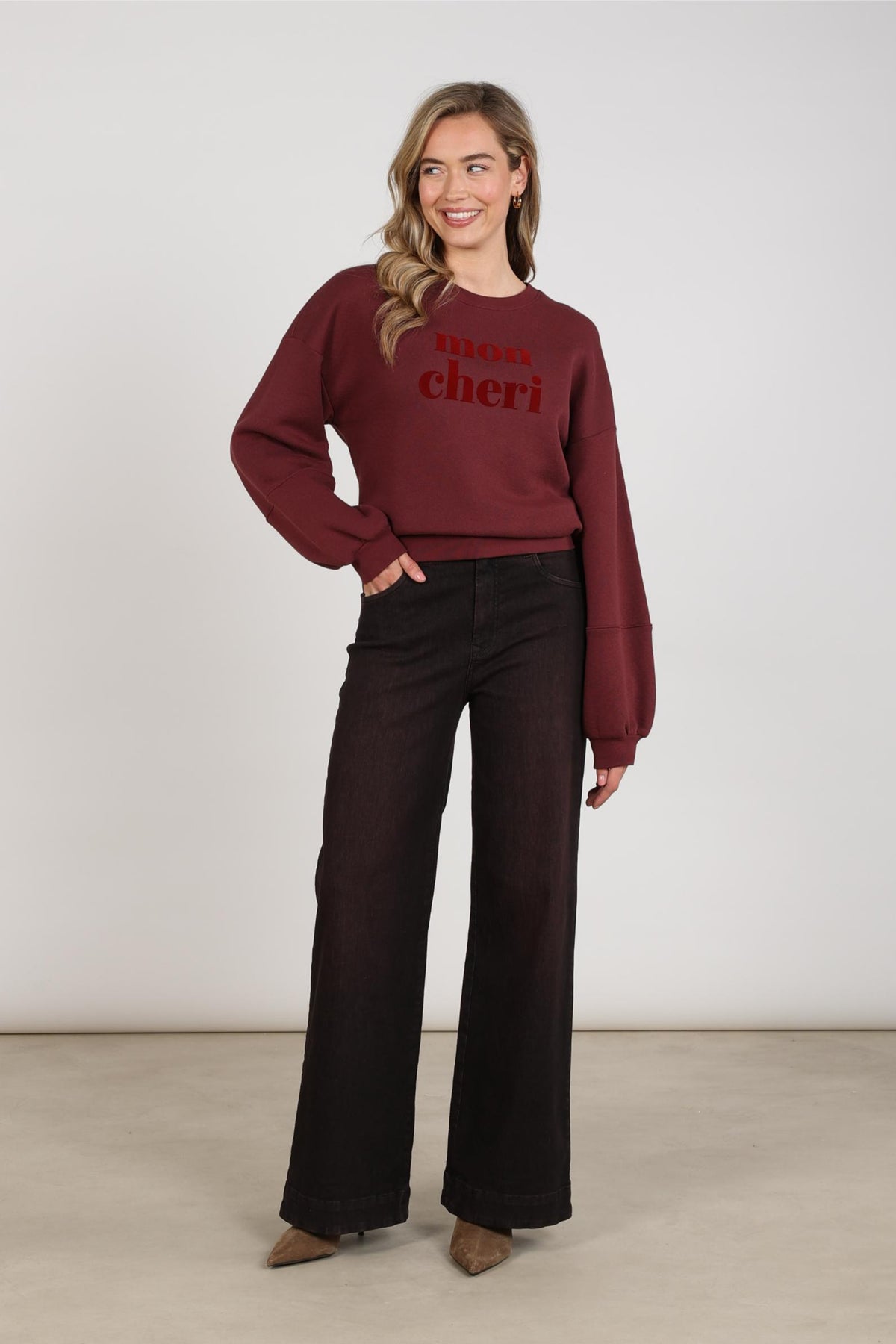 Nukus Abby Cherry jeans in donkerblauw denim met rechte pasvorm en opvallende rode stiknaden, hangend aan een houten kapstok.