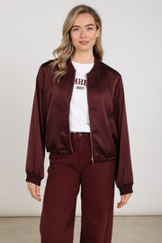 Nukus Dena Shiny Cherry jas met glanzende rode afwerking en capuchon, gedragen door een model.