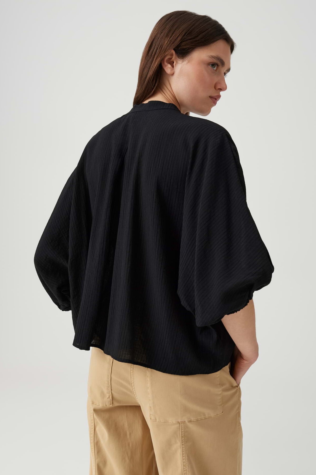 Zwarte blouse van Opus Fylora met losvallende pasvorm en ronde hals, hangend aan een kapmantel.