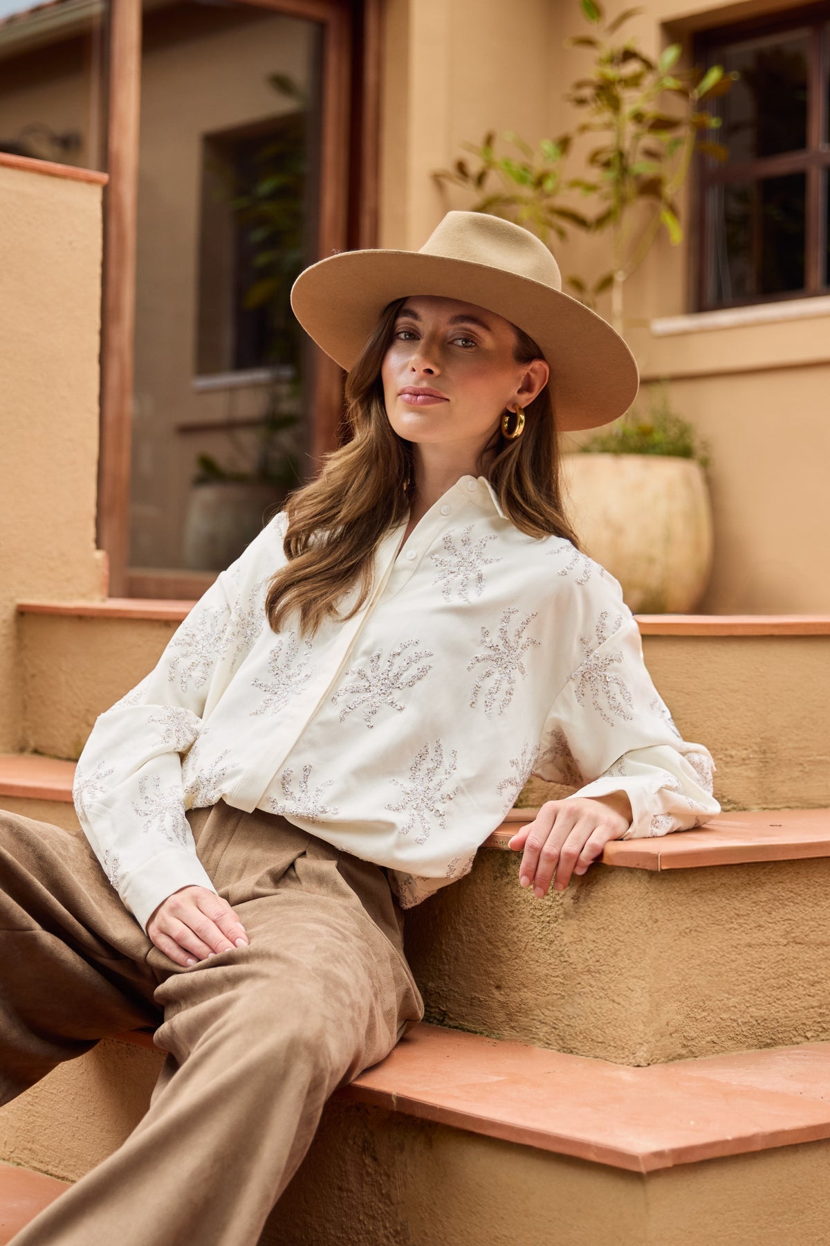 Lichte offwhite blouse Aster Paillet van Nukus met glanzende pailletten en lange mouwen, gedragen door een model.