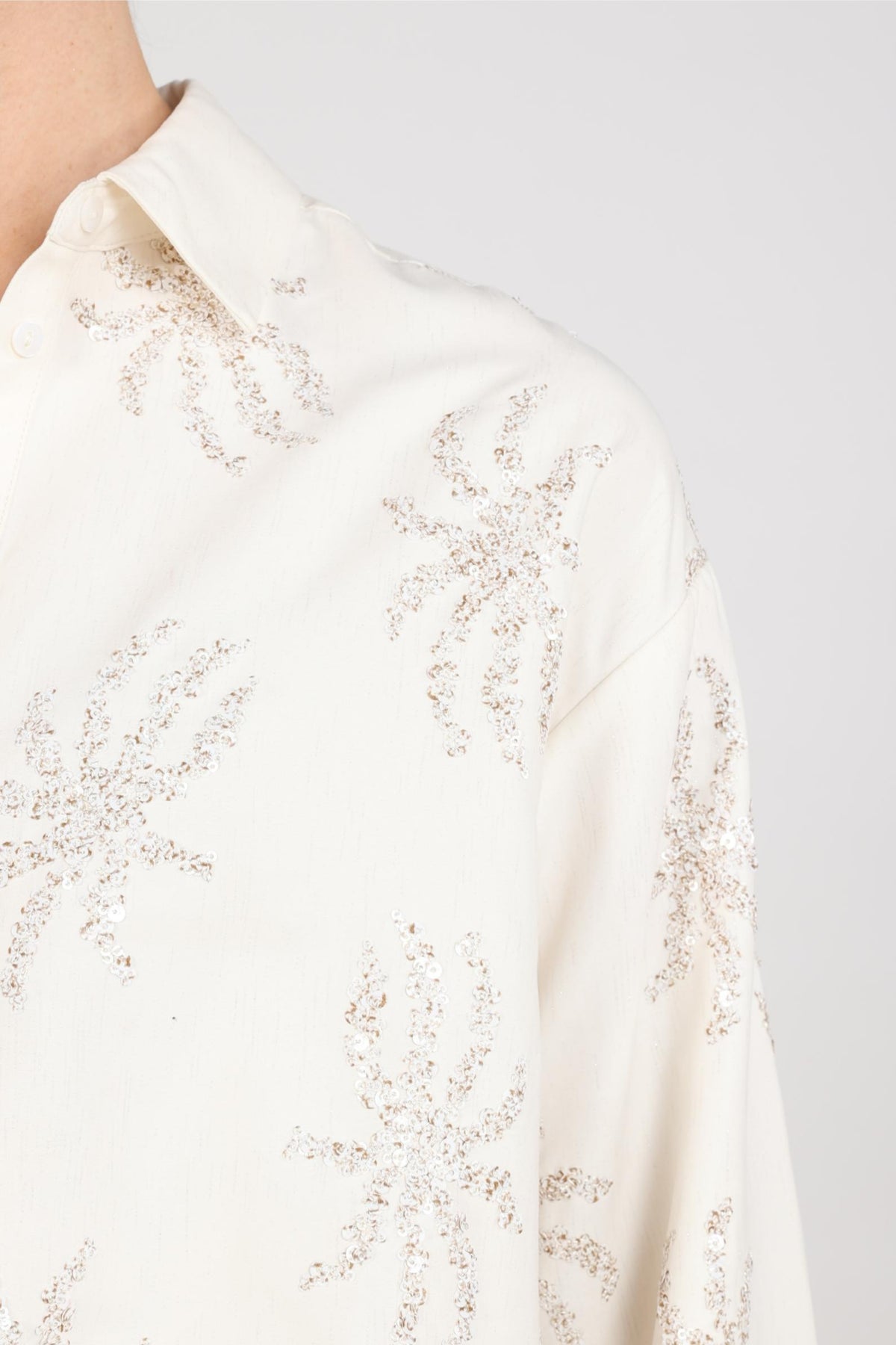 Offwhite paillet blouse van Nukus met elegante pasvorm en decoratieve pailletten, getoond op een model.