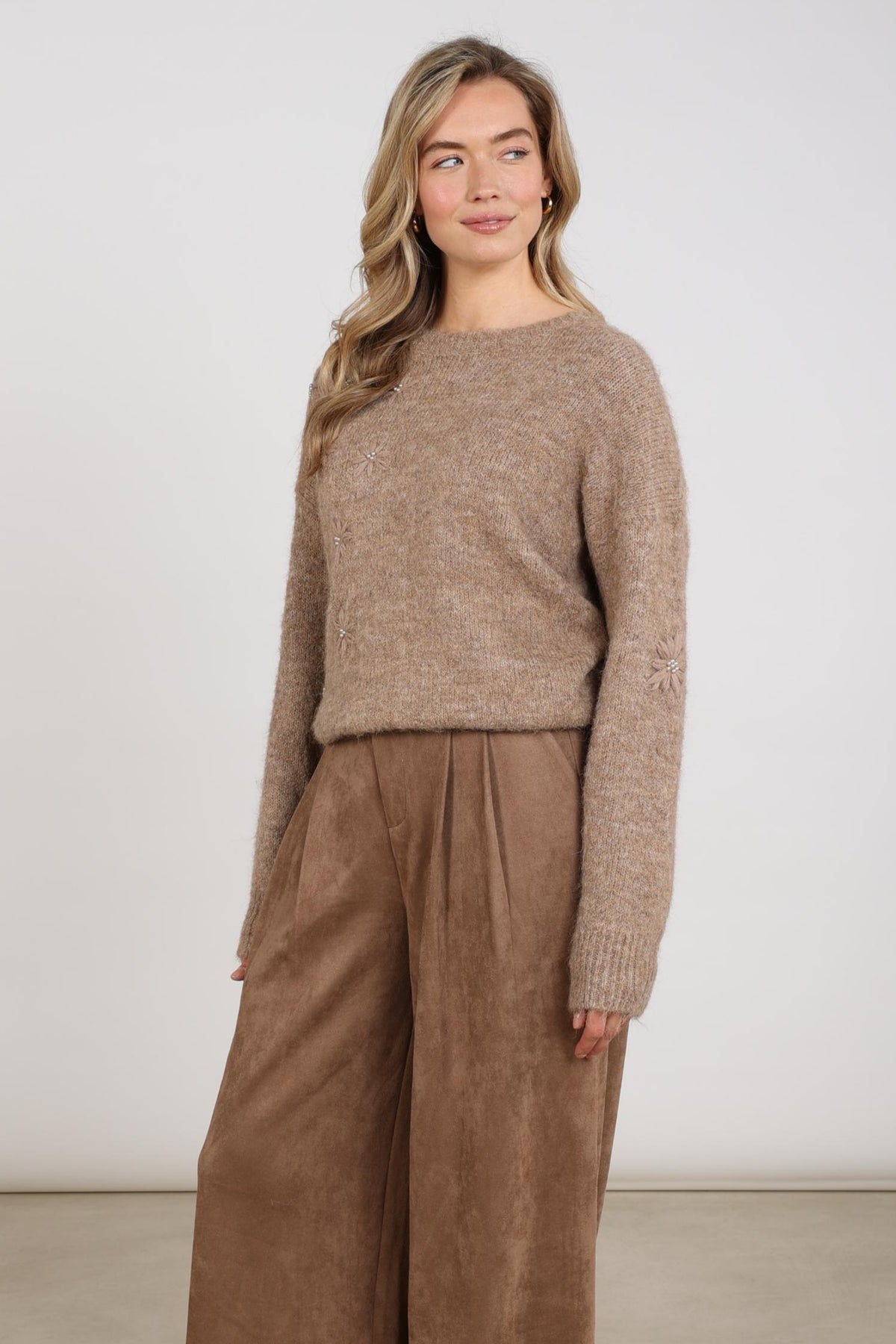 Taupe Nukus trui Konstanza Flower met bloemenpatroon en ronde hals, gedragen door een model.