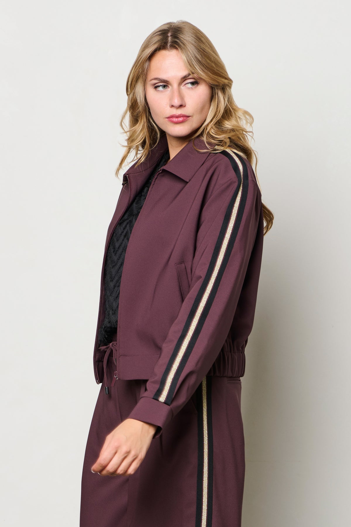 Donkerpaarse &Co woman Faith jas in auberginekleur met stijlvolle pasvorm en rits, gedragen door model op straat.