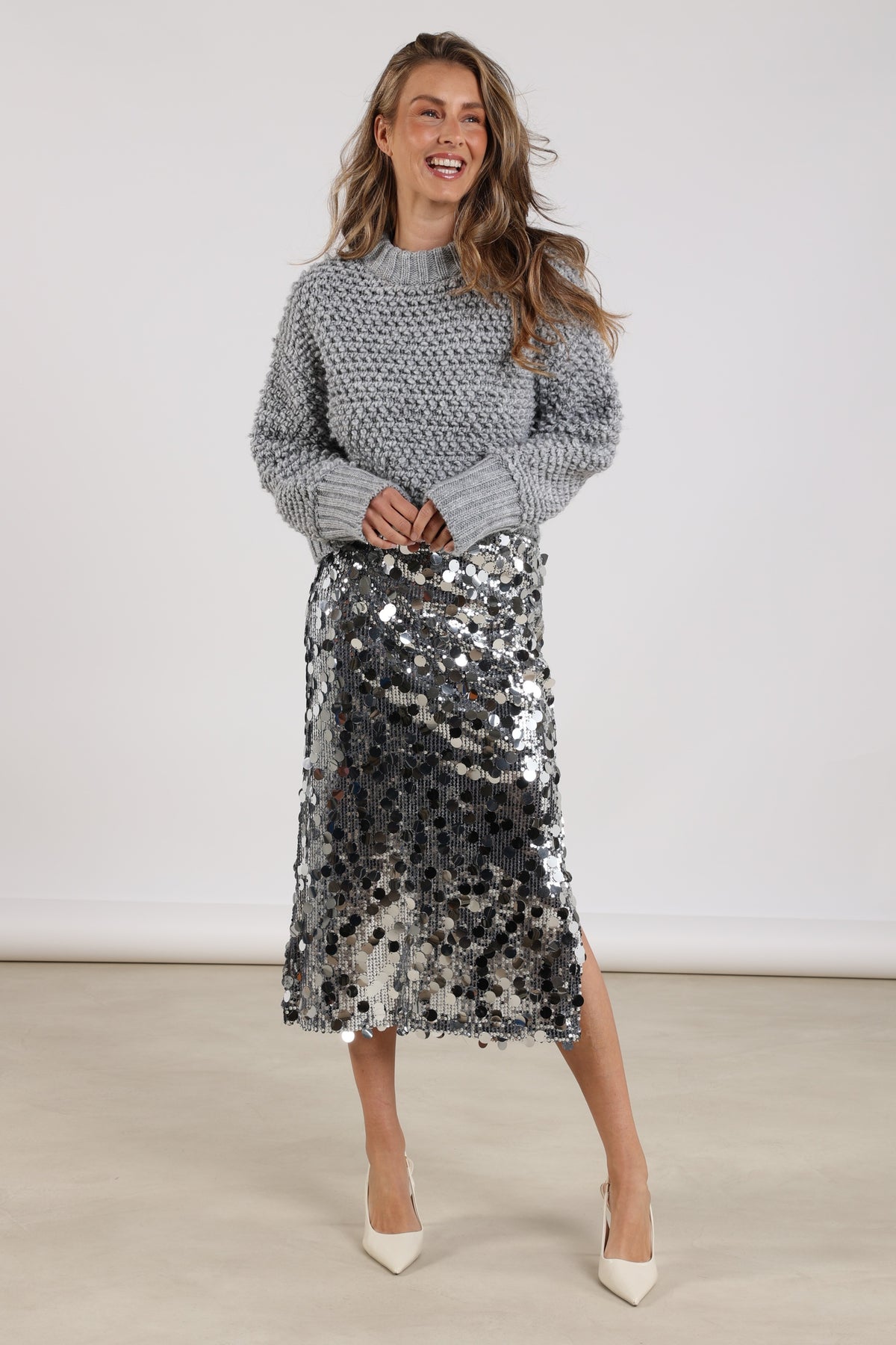 Zilveren pailletten rok Bella van Nukus, glanzende details, vloeiend model, op een roze achtergrond.