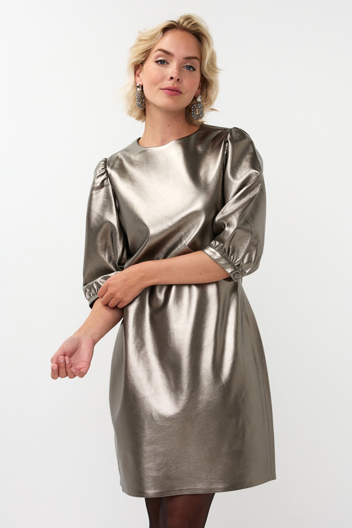 Zilveren PU jurk van EsQualo, model Larissa, met elegante pasvorm en glanzende afwerking, gedragen door een model.
