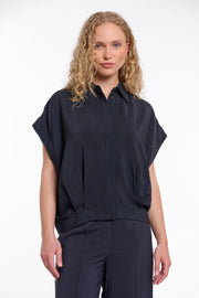 Donkerblauwe blouse Imela van Rino & Pelle met lange mouwen en knoopsluiting, hangend aan een kapstok.