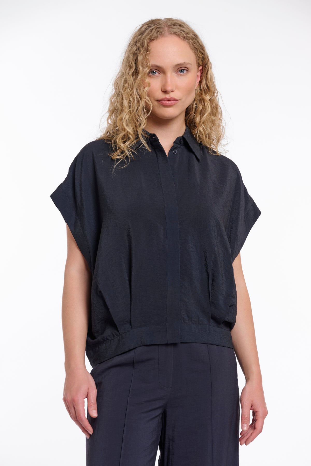 Donkerblauwe blouse Imela van Rino & Pelle met lange mouwen en knoopsluiting, hangend aan een kapstok.