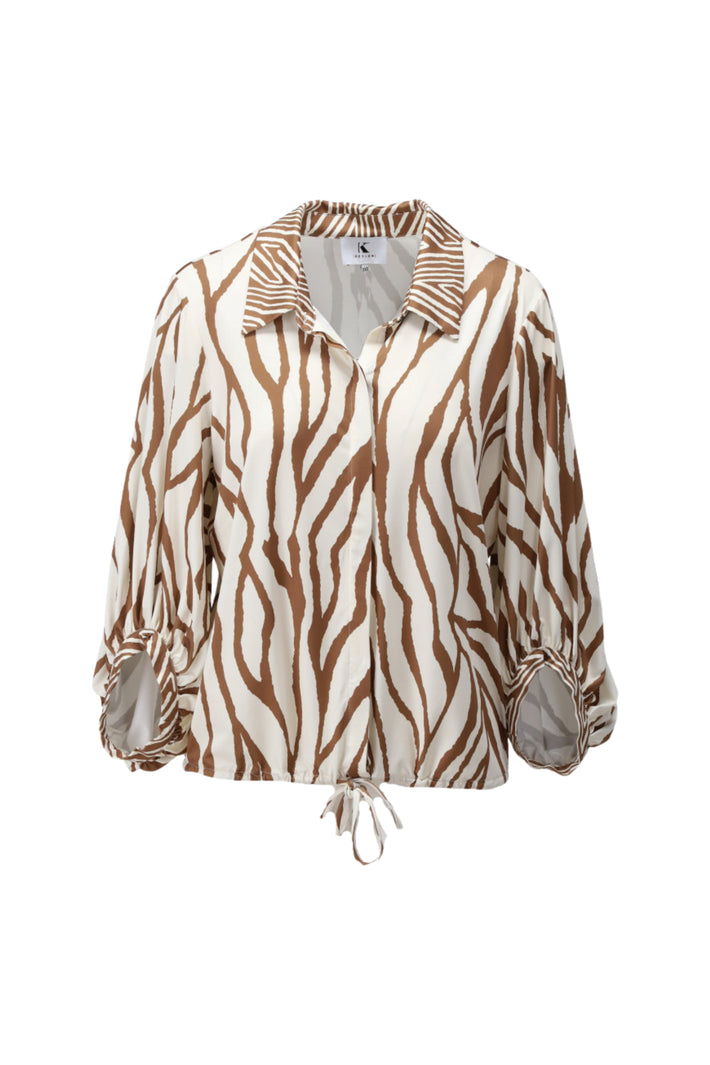 K-design blouse met uniek design in zachte kleuren en elegante pasvorm, gedragen door model op lichte achtergrond.