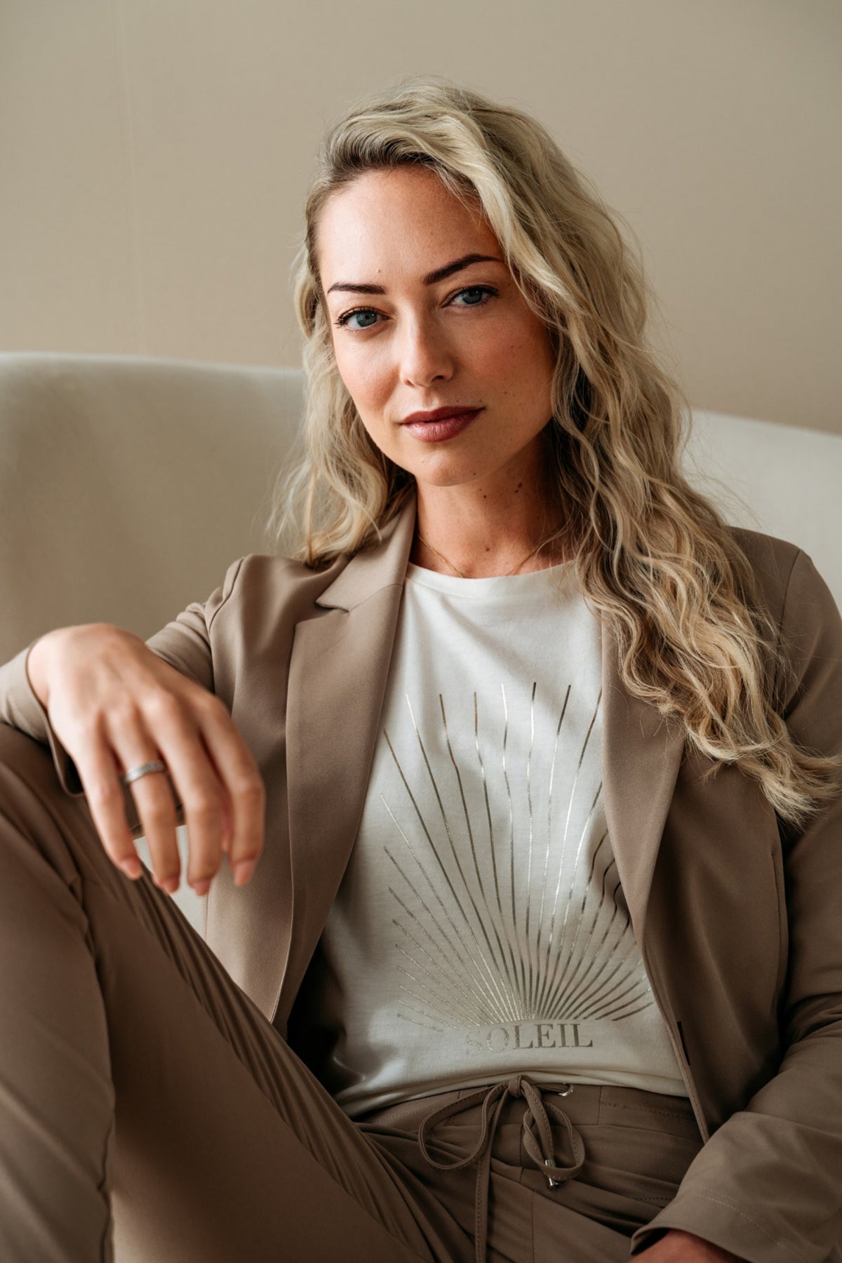 Taupe reiskostuumblazer voor dames van &Co woman, getoond op model, met knoopsluiting en stijlvolle pasvorm.
