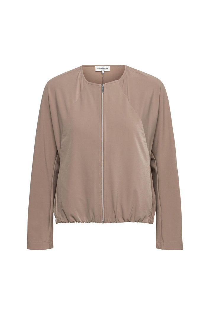 Reisjasje Pihla in taupe van &Co woman, getailleerd met rits en zakken, gedragen door model, close-up van de jas.