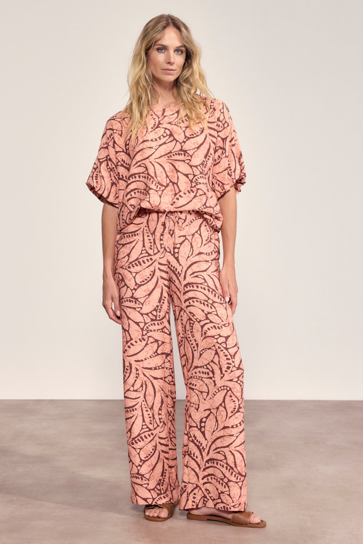 Lieve peachkleurige Tramontana Leaf Luxe Print broek met opvallend bladpatroon, model Larissa, voor een elegante look.