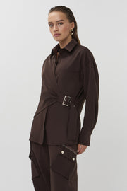 Bruine blouse van Studio Amaya met losse pasvorm en ronde hals, gedragen door een model, close-up van de stof en details.