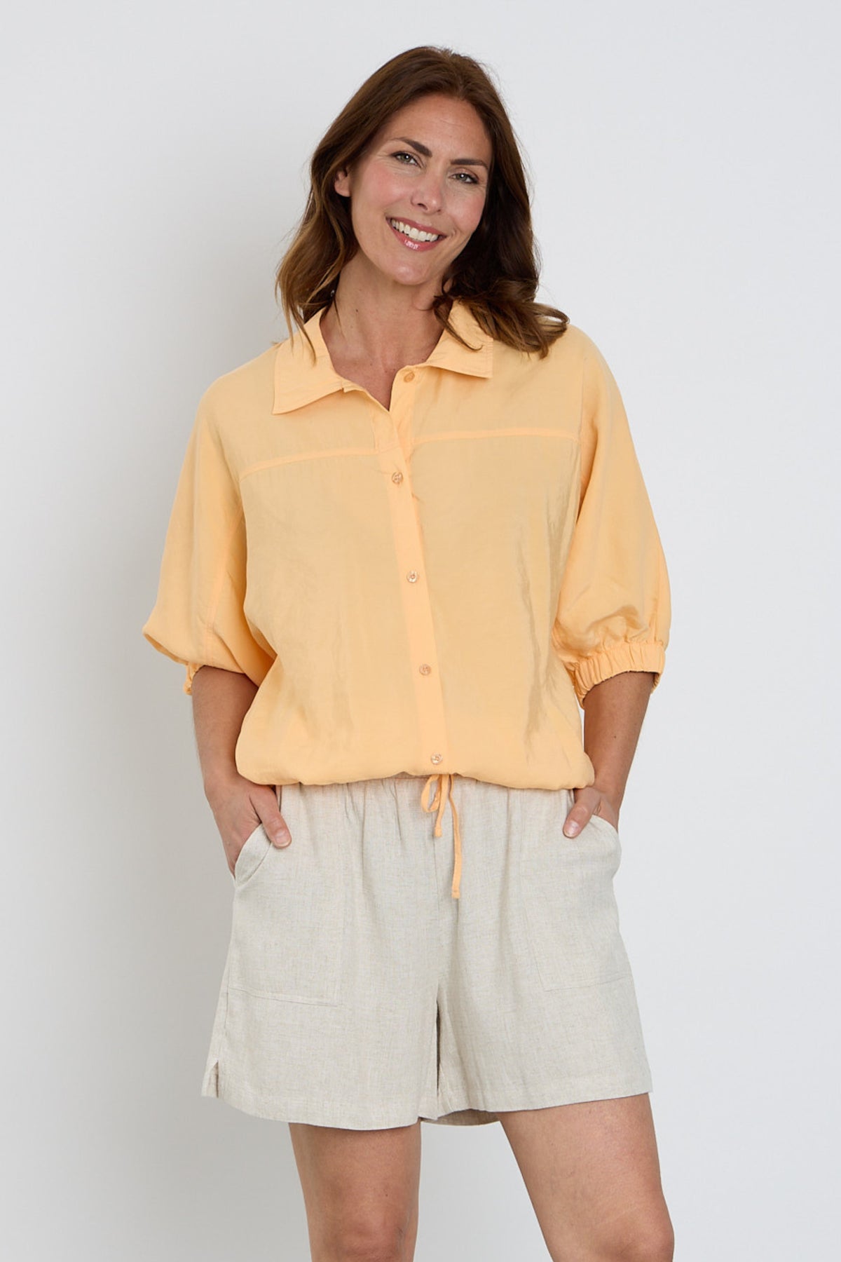 Zoso blouse Lisa Apricot met lange mouwen en knoopsluiting, gedrapeerd op een mannequin, close-up van de textuur en pasvorm.