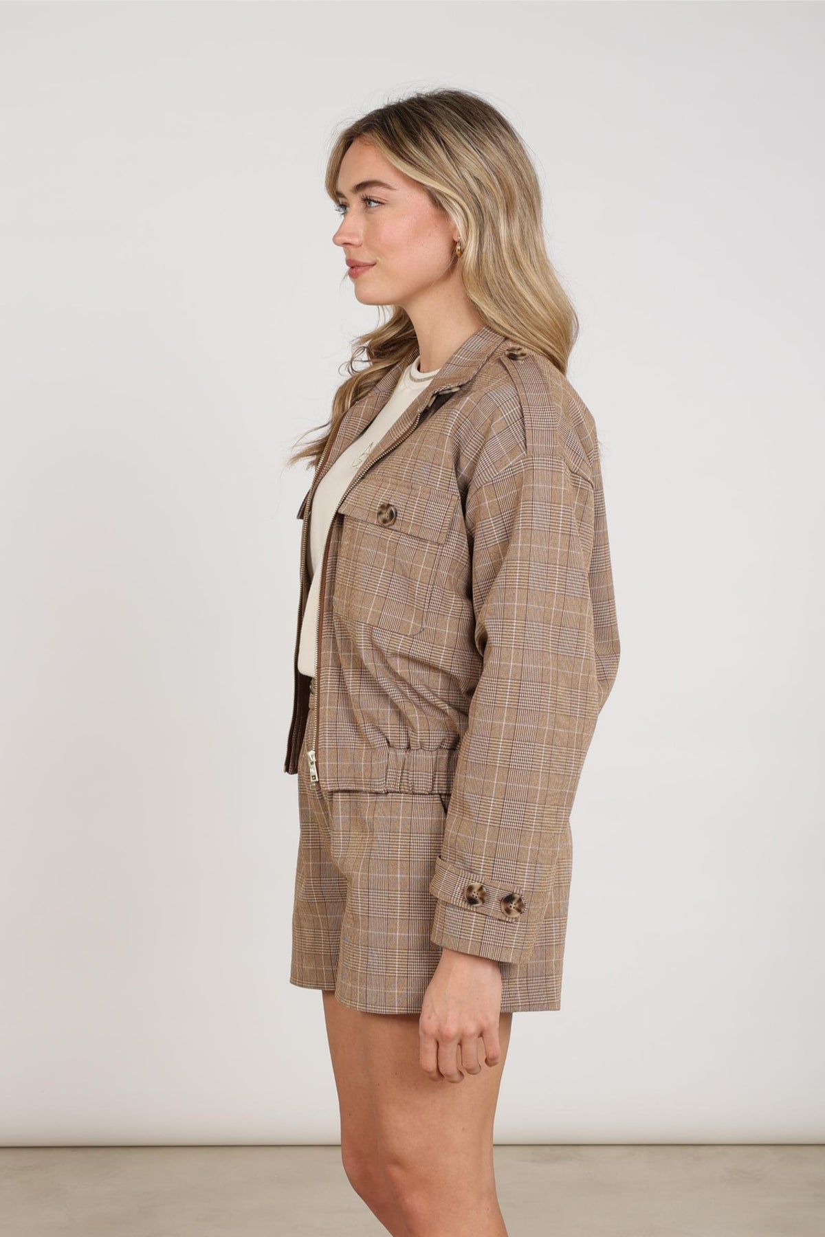 Nukus Hope Check Toffee jas met ruitpatroon en knopen, gedragen door een model, zichtbaar op de afbeelding.