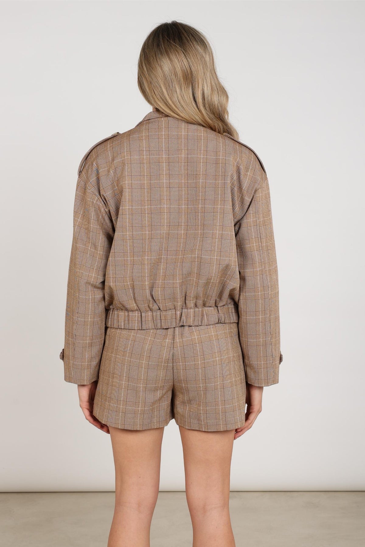 Nukus Hope Check Toffee jacket, geruit met knopen en kraag, gedragen door een model, close-up van de stijlvolle buitenjas.