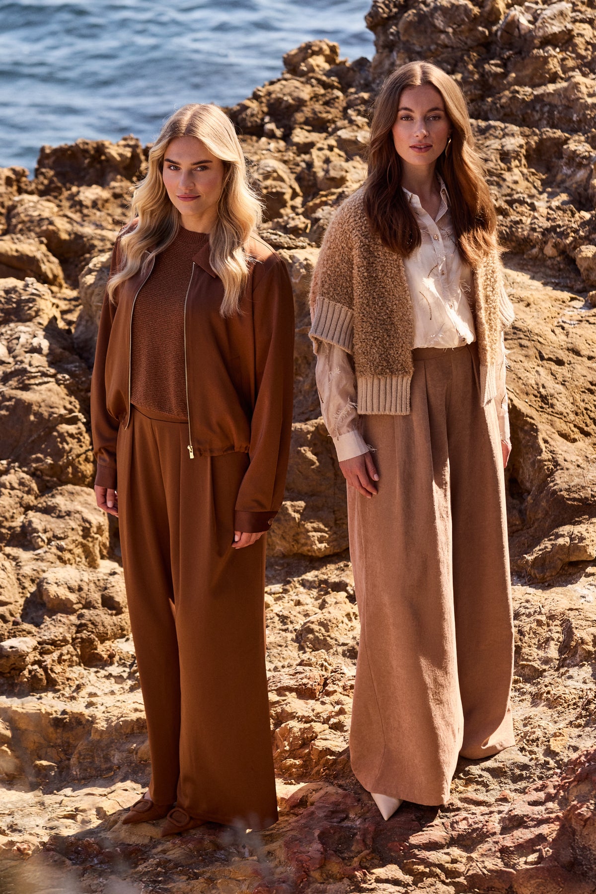 Nukus broek June Shiny Espresso met glanzende stof en rechte pasvorm, gedragen door een model, close-up van de look.