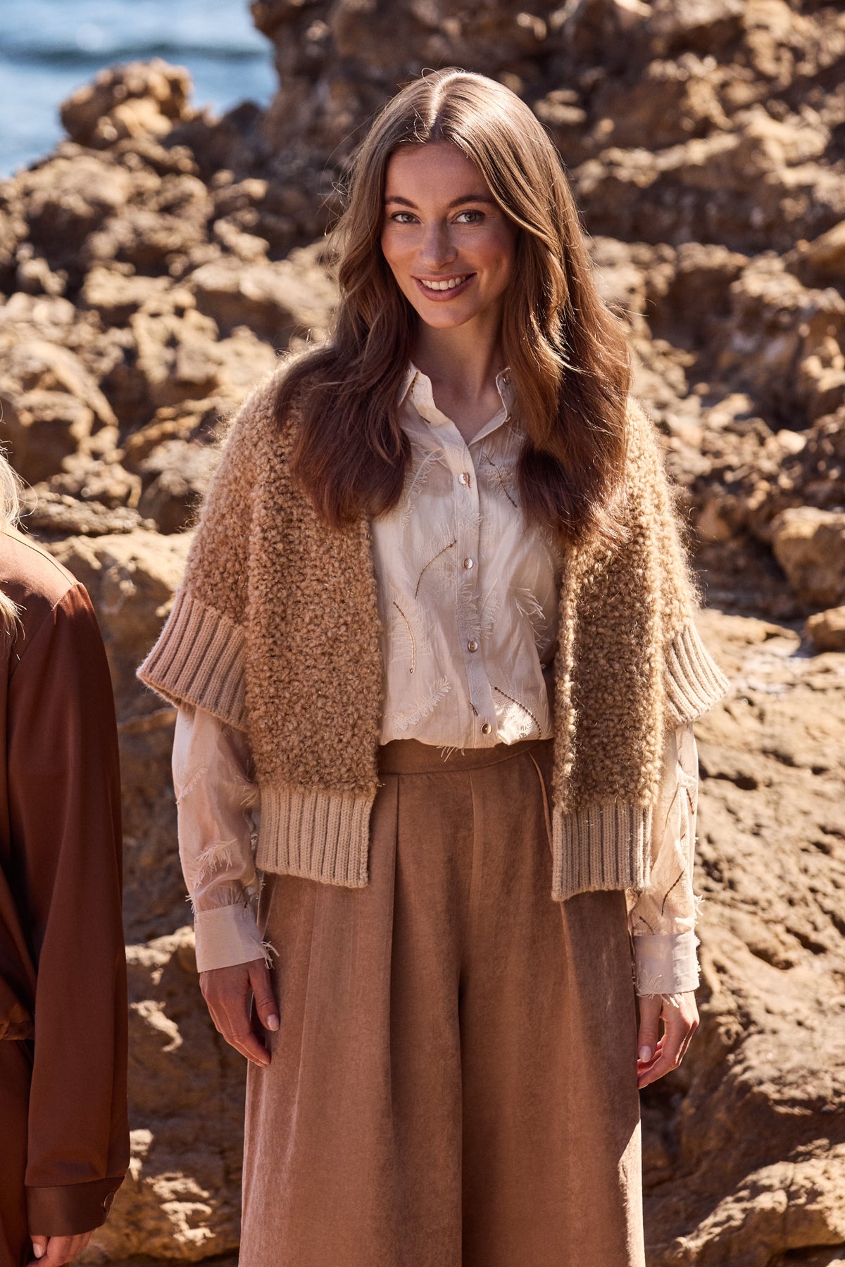 Zandkleurige blouse Aysha met verenprint van Nukus, zichtbaar op een model, met elegante pasvorm en stijlvolle details