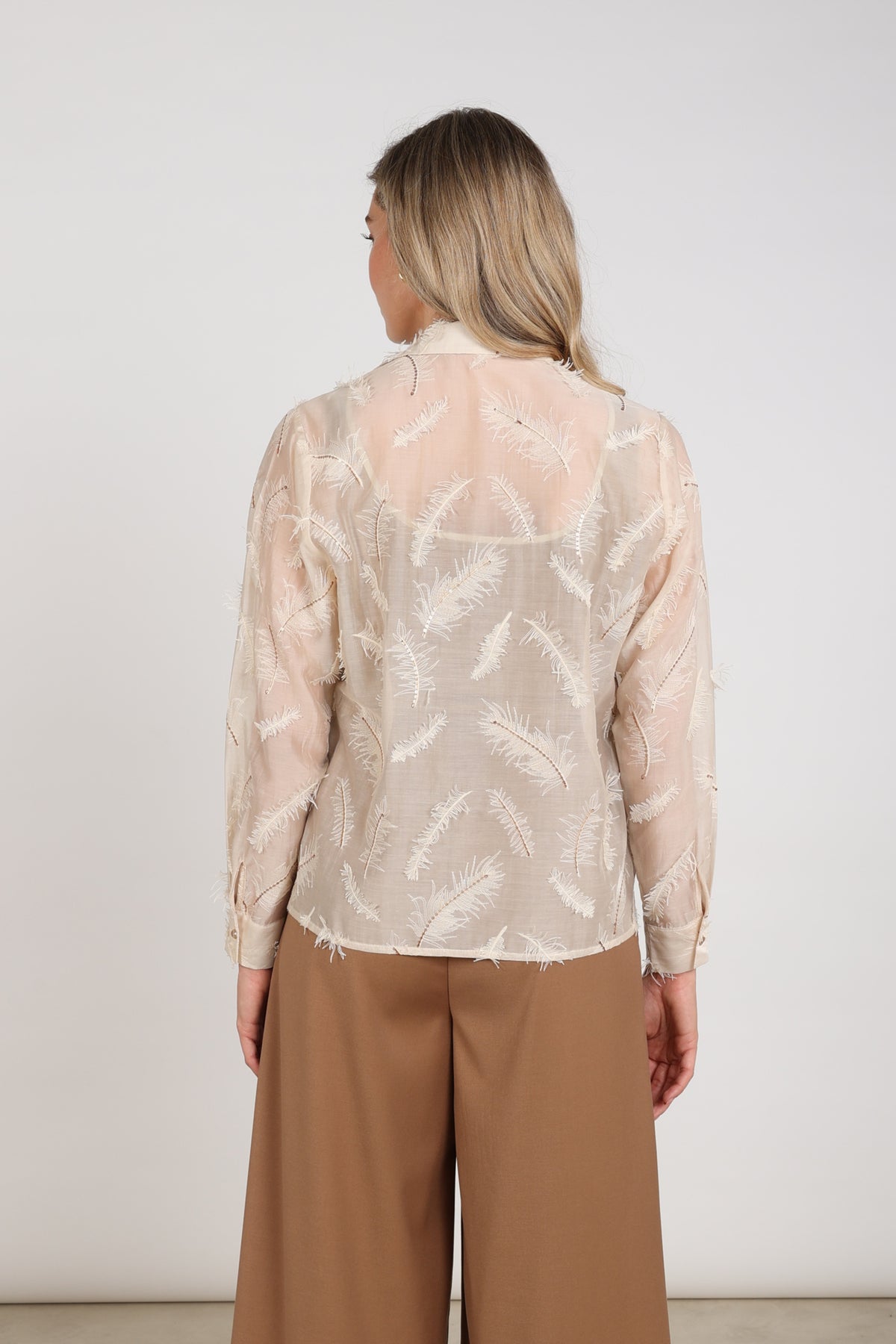Nukus blouse Aysha met veren in zandkleur, licht en elegant, zichtbaar in de afbeelding op een model.