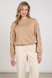 Donkere toffeekleurige trui Sara van Nukus met pailletten, gedragen door een model, close-up van de stof en details.