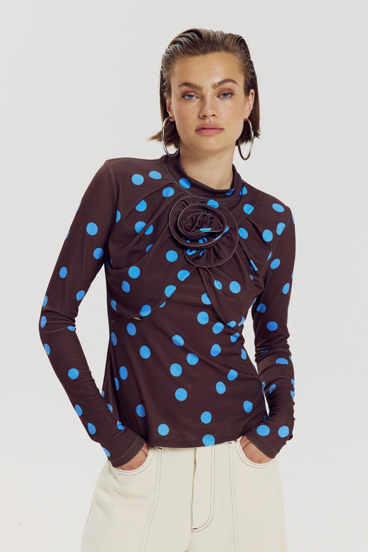 Blauwe polkadot top van Harper & Yve, model Jose, met stijlvol ontwerp en ronde hals, gedragen door een model.