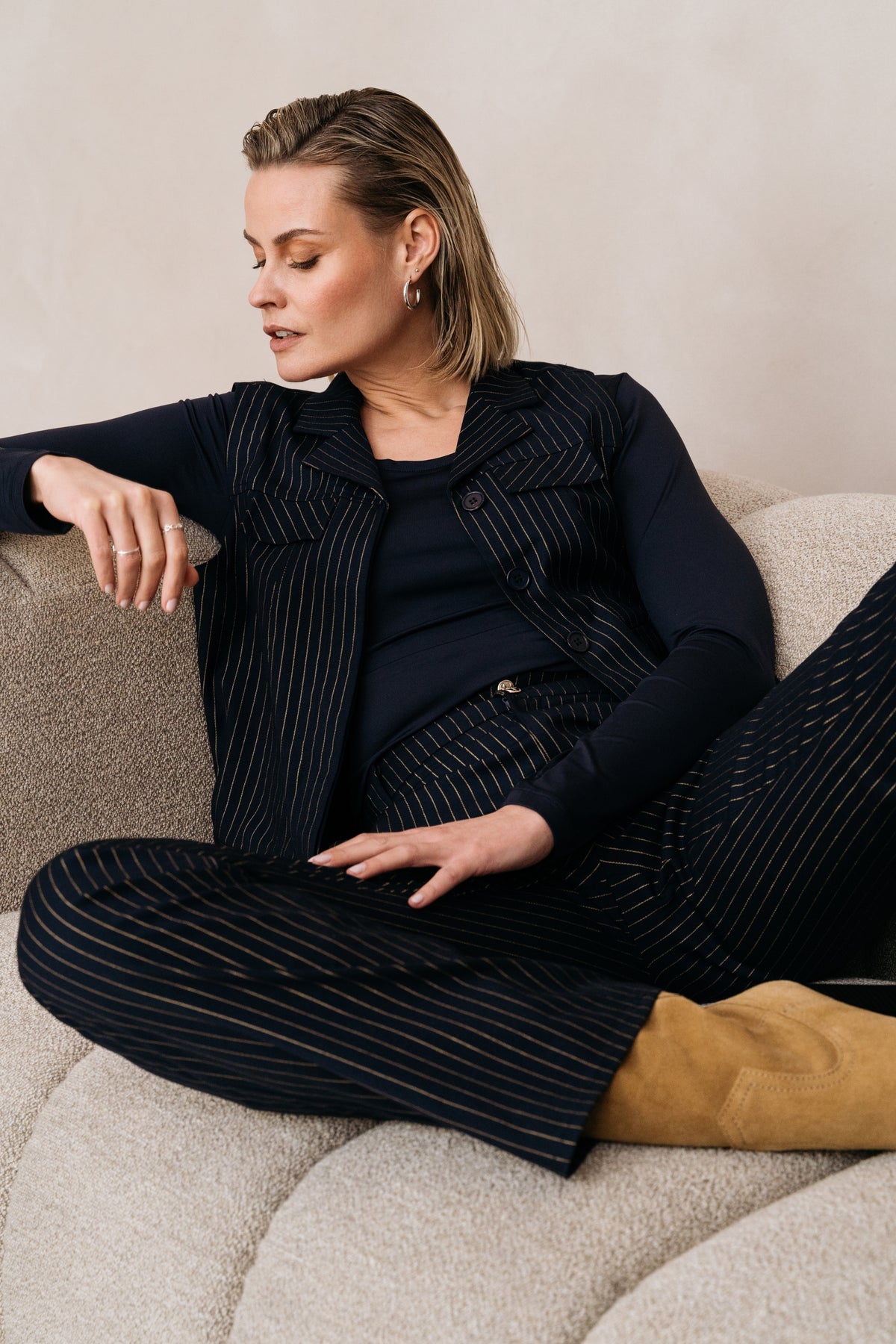 Donkere pinstripe broek van Maicazz & Zizo met gouden details, model LARISSA draagt de Philia Pinstripe Gold broek.