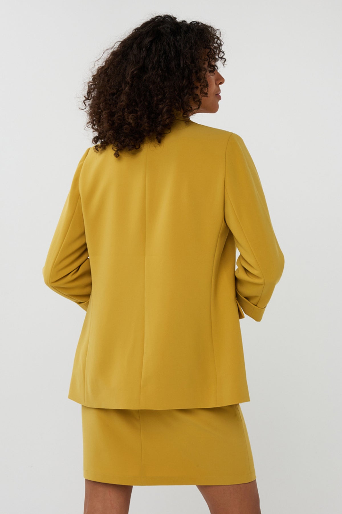 Gouden olijfgroene blazer van EsQualo Turn Up City, gestijld en gedragen door Mandy, voor een stijlvolle look.