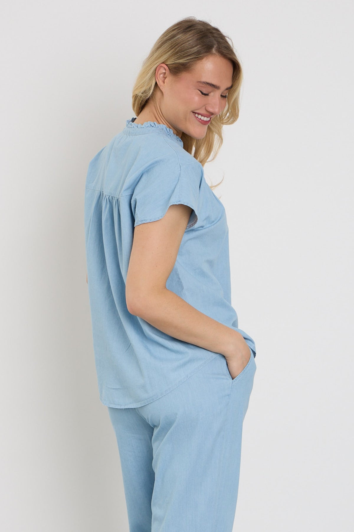 Lichte blauwe blouse van Elvira Casuals, model Rosan, met elegante pasvorm en knopen, gedragen door een model.