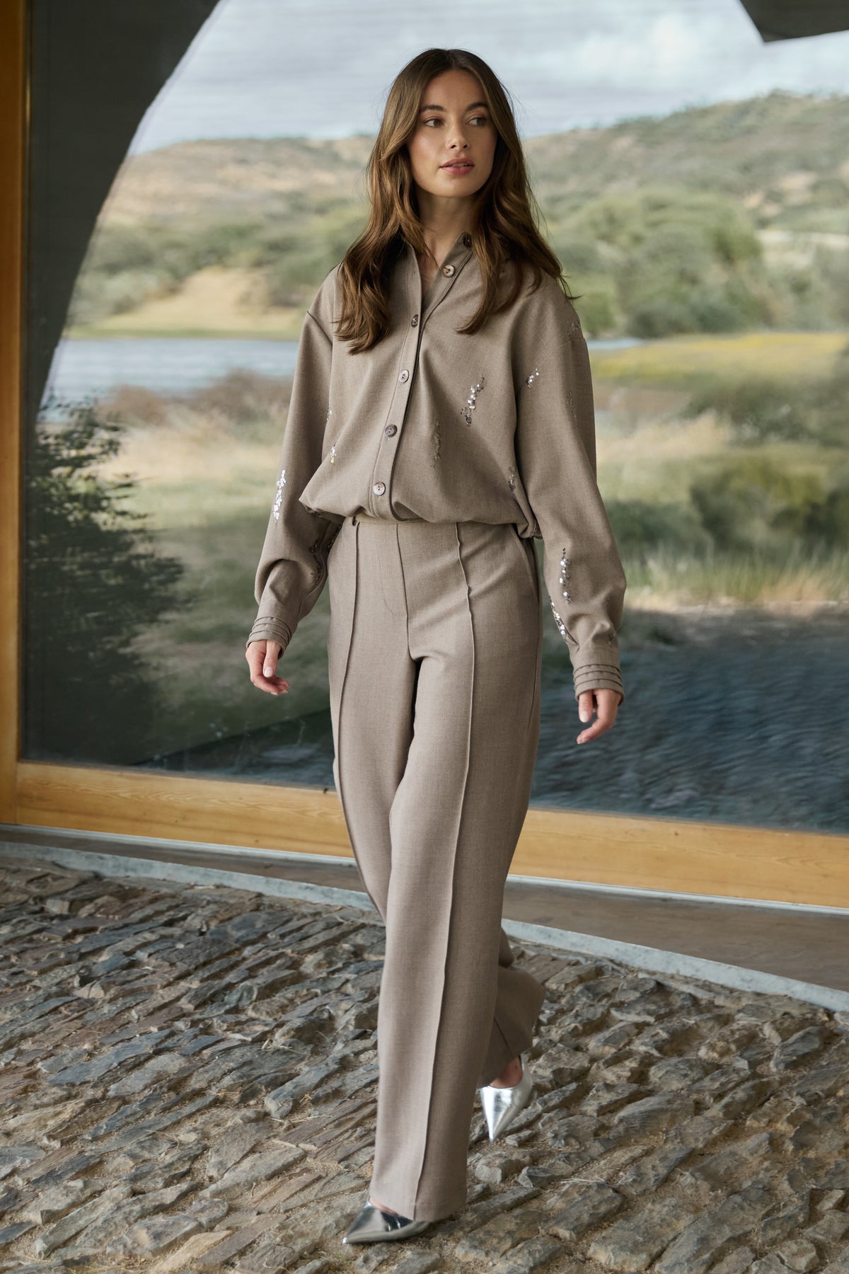 Taupe Nukus broek Jill met rechte pasvorm en elastische taille, zichtbaar in de afbeelding.