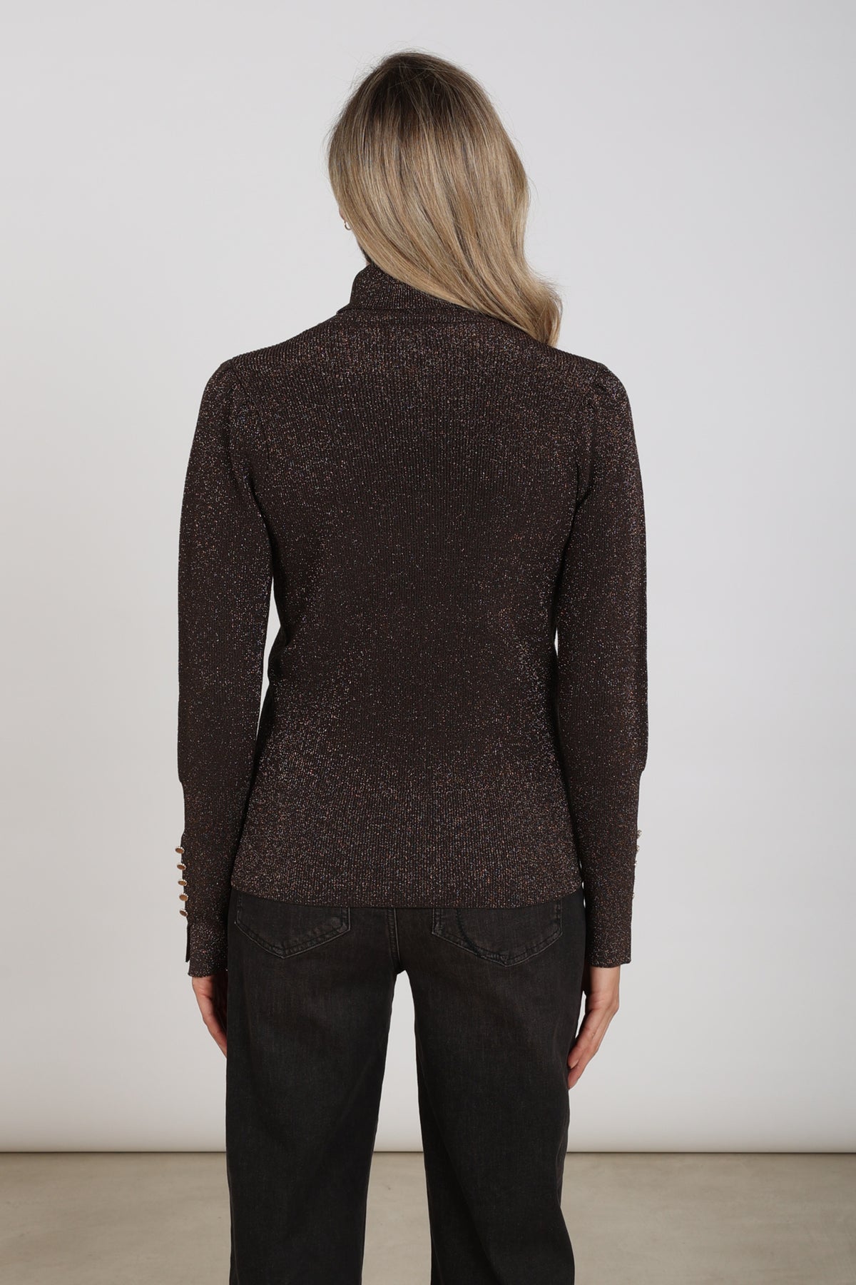 Donkere chocolade Sylvia Lurex trui van Nukus met glanzend lurex detail, gedragen door een model.