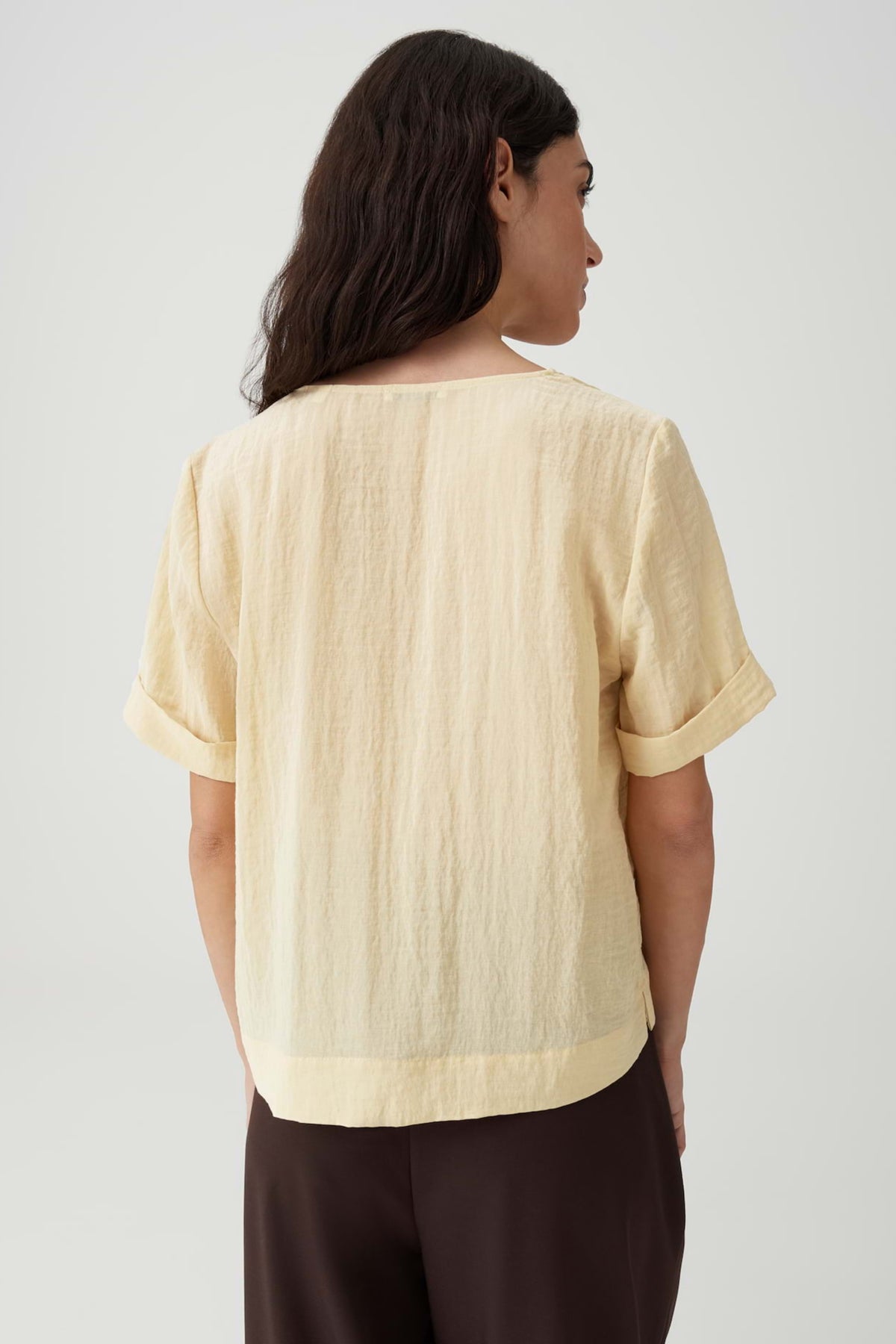Lichte blouse Filkara Honey Butter van Opus, met ronde hals en lange mouwen, hangend op een kapstok.
