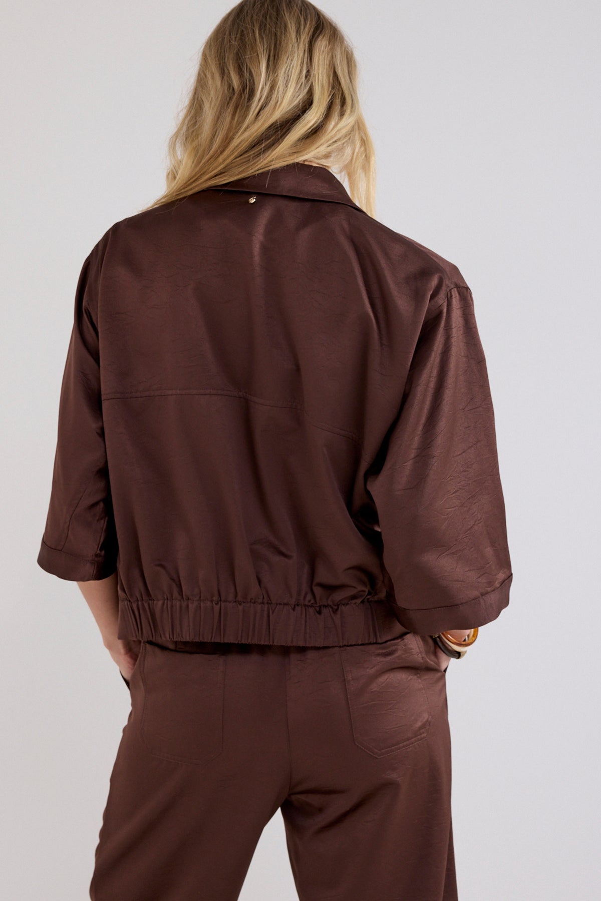 Elastische chocoladebruine blouse van Tramontana, getoond op een model met details van de stof en pasvorm.