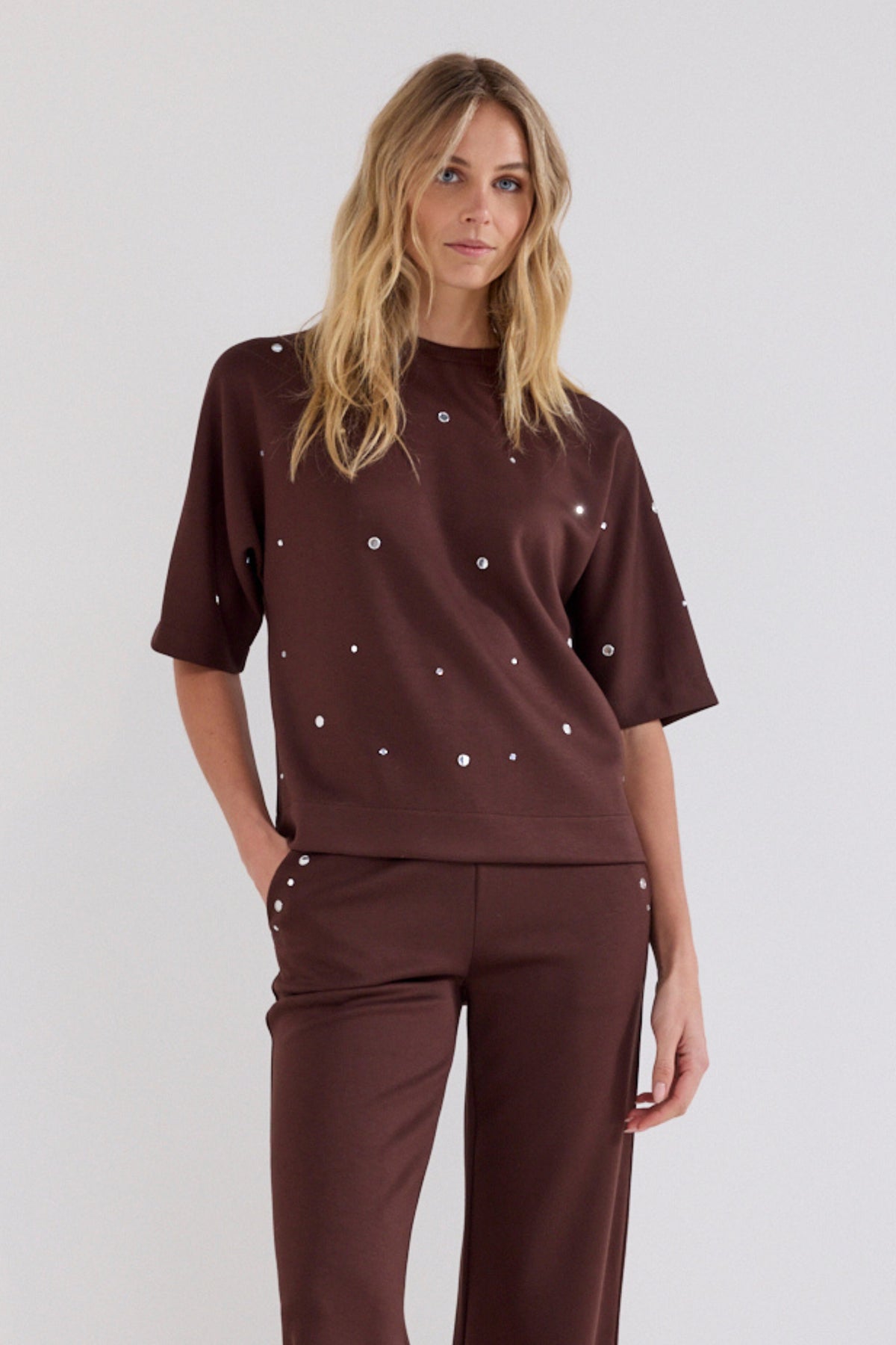 Donkere chocolade Tramontana sweattrui met ronde hals en zachte stof, gedragen door een model tegen een neutrale achtergrond.