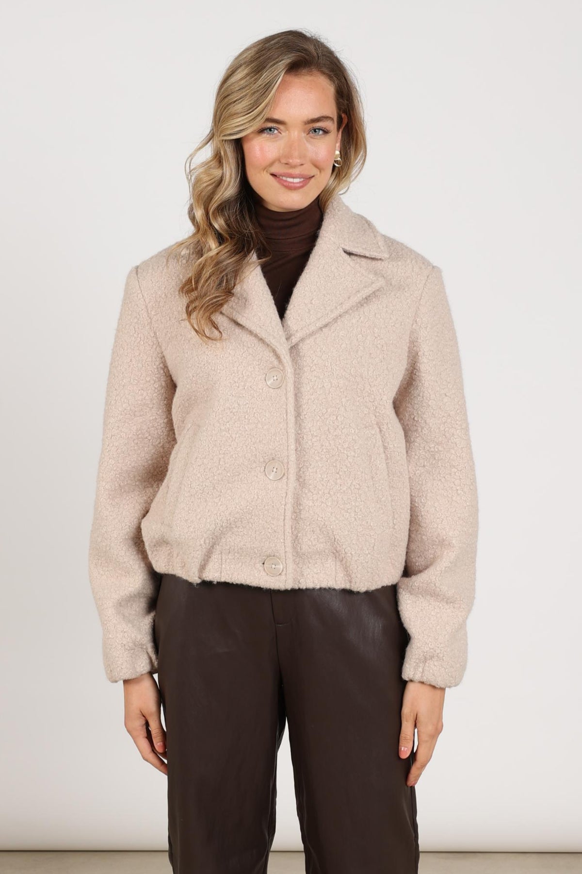 Nukus Madelin Bouclé Sand jas met ronde kraag en knopen, stijlvolle damesjack in beige met textuurrijke stof.