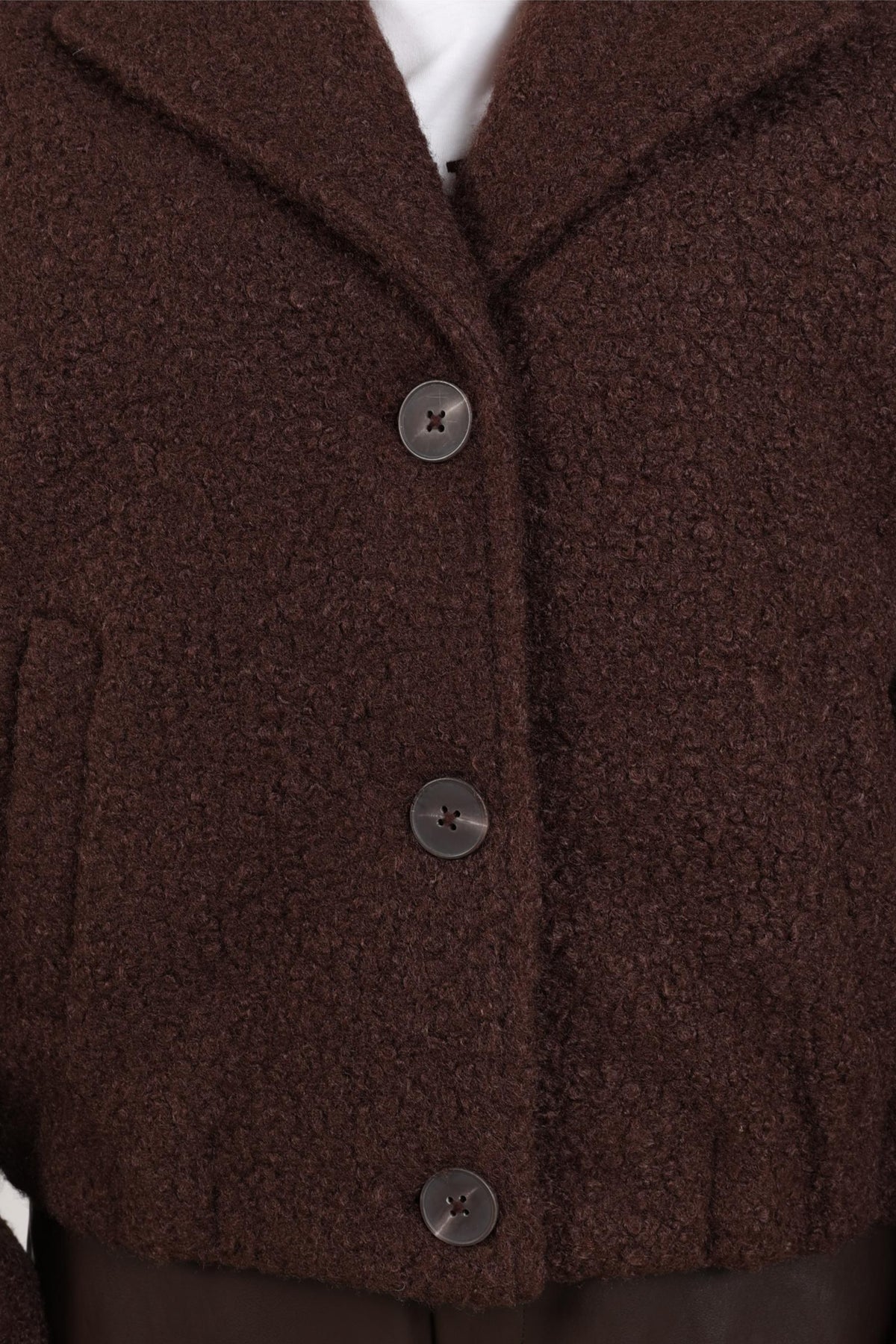 Donkerbruine Nukus Madelin Bouclé jas met stijlvolle textuur en knoopsluiting, gedragen door een model.